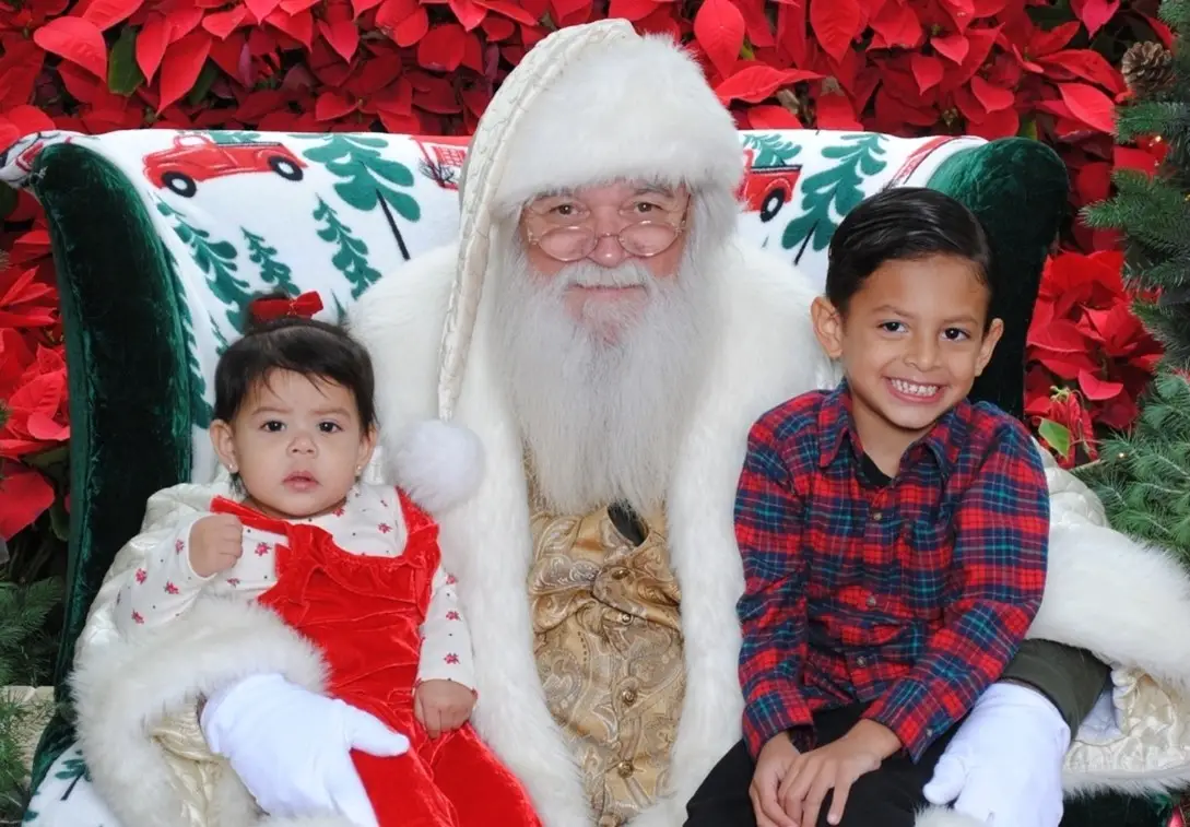 Santa Claus posing with two children at Biltmore Fashion Park during a holiday event for pictures with Santa.