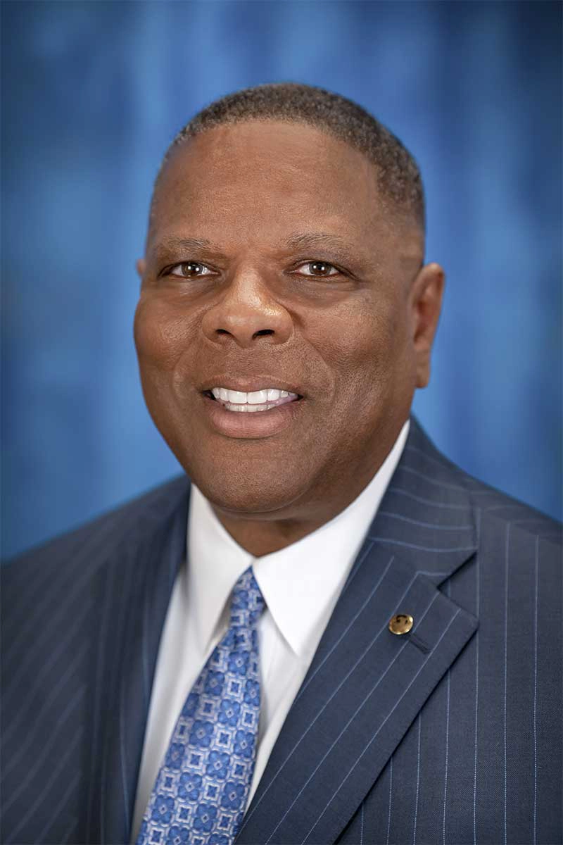 Councilman Kevin Robinson smiling in a professional headshot wearing a blue pinstripe suit and patterned tie.